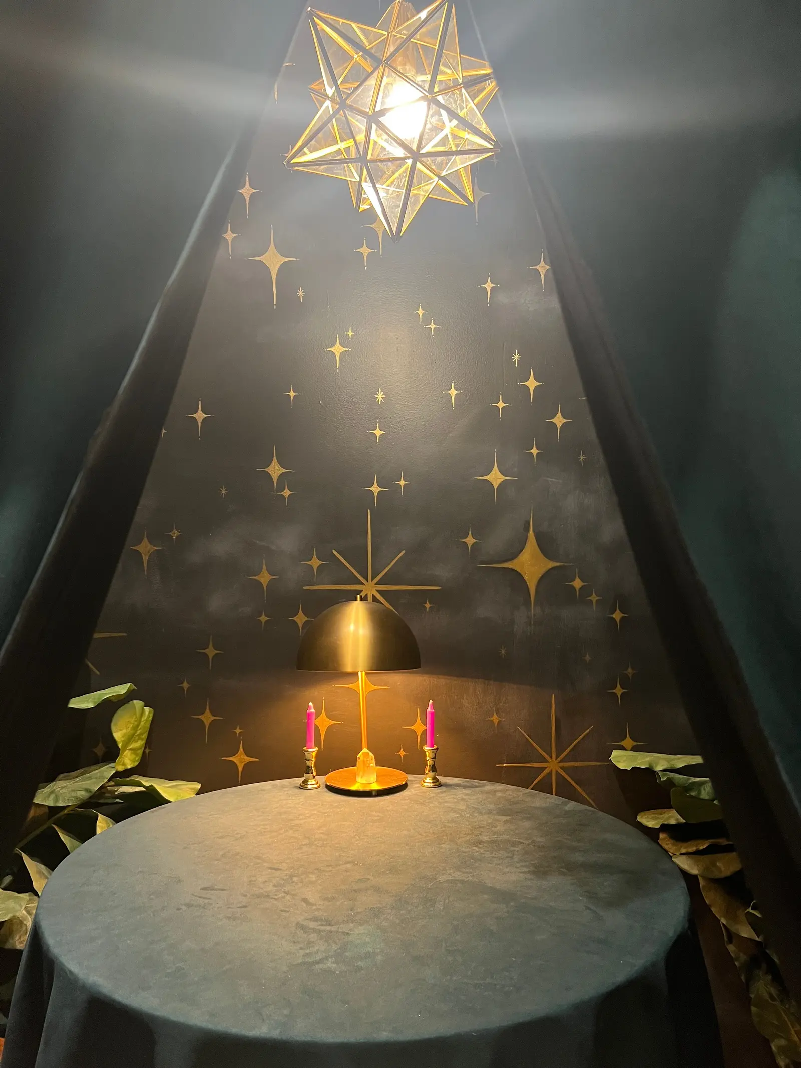 A painted alcove ceiling scattered with gold stars, a faceted lantern hanging above a small round table set with lit candles
