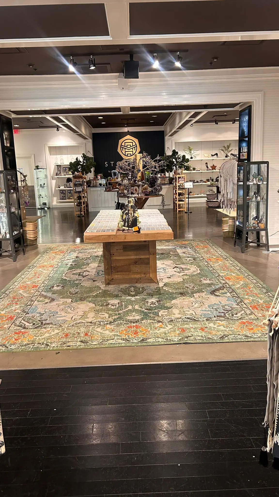 The Kennesaw store: white walls and lit shelving down both sides, a long timber display table on a patterned rug, dark timber floor